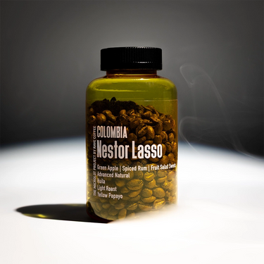 A bottle of coffee beans labeled 'Nestor Lasso' filled with roasted coffee beans, shown on a dark gray background with dramatic lighting and a soft smoke effect.