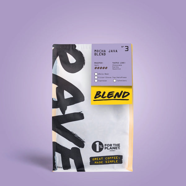 A bag of Mocha Java Blend Nº 3 coffee beans on a lavender background. The white packaging with bold black text and a yellow label highlights 1% for the Planet and Great Coffee, Made Simple—ideal for bold coffee lovers.