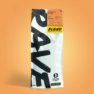 A 1kg bag of Espresso Blend Nº 4 stands upright on a warm orange background. The white bag shows bold black RAVE text, a bright yellow label, and notes its balanced coffee flavor and certifications.