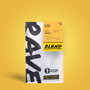 A bag of Fudge Blend Nº 5 coffee beans sits on a yellow background. The white packaging with bold black and yellow accents features “RAVE” branding, ideal for brewing flat whites or cappuccinos with fudge-like flavor notes.