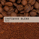 Whole coffee beans and ground coffee are displayed. Across the center, a beige label reads 