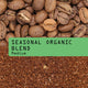 Close-up of whole Guatemalan coffee beans next to ground coffee, separated by a green label reading Seasonal Organic Coffee Blend Nº 7 in bold black text.