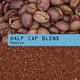A pile of whole beans sits atop ground coffee, with a blue label reading Half Caf Blend Nº 13 Medium—highlighting this low-caffeine, smooth medium roast created for those seeking balanced coffee enjoyment.
