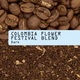 Close-up of whole coffee beans on top, ground coffee on the bottom. A pale blue label in the center reads “Colombia Flower Festival Blend Nº 25” in black typewriter-style font. This limited-release blend from RAVE COFFEE highlights premium Colombian beans, expertly crafted to deliver a distinctive, medium-dark roast profile.