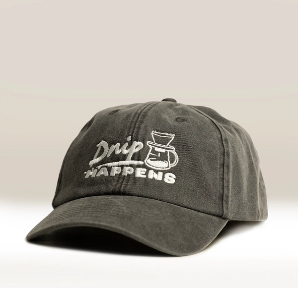 The Drip Happens Hat by RAVE COFFEE is a vintage black cap with white "Drip Happens" embroidery above a coffee carafe, featuring an adjustable strap and shown against a neutral background.