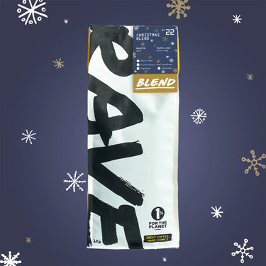 A one-kilogram bag of RAVE COFFEE Christmas Blend Nº 22 coffee beans featuring a dark roasted blend label, snowflake patterns, and a 1% for the Planet logo.