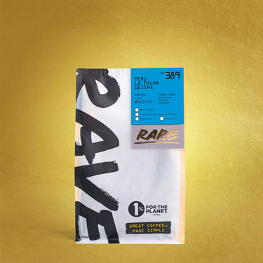 A bag of Rare Coffee Roastery whole bean coffee, specifically Peru La Palma Gelisha, standing upright against a textured gold background. The packaging is white with bold black brushstrokes on the left side, a bright blue label on the upper right, and a brown 'RARE' brand label in the center.