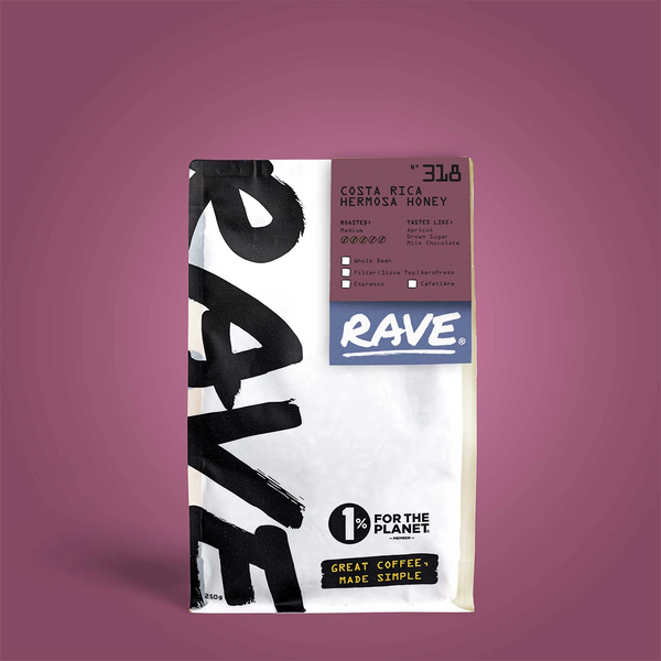 A white RAVE COFFEE bag labeled Costa Rica Hermosa Honey Nº 318 features tasting notes and a 1% for the Planet logo, set against a purple background—ideal for eco-conscious coffee lovers.