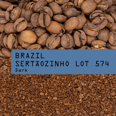Coffee beans with a label indicating 'Brazil Sertáozinho Lot 574 Dark' on a background of ground coffee.