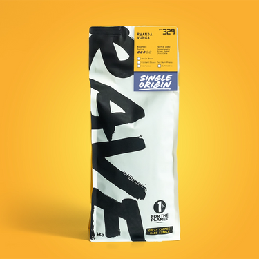 A white RAVE COFFEE bag stands upright against a yellow background. A yellow label highlights Rwanda Vunga Nº 329 Single Origin, a medium roast with tasting notes from the renowned Vunga washing station.
