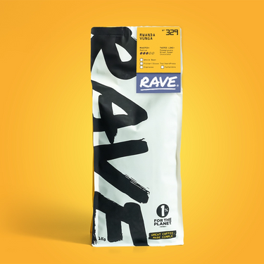 A white and black RAVE COFFEE bag of Rwanda Vunga Nº 329 stands upright on a yellow background. The top label shows the coffee name and details, while a 1% for the Planet logo appears at the bottom, highlighting its quality.
