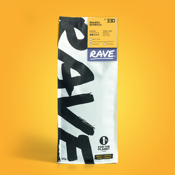 A white and black bag of RAVE COFFEE stands upright against a yellow background. The label reads Rwanda Bumbogo Nº 330, highlighting this fruity coffee’s flavor, weight, and the “1% for the Planet” logo.
