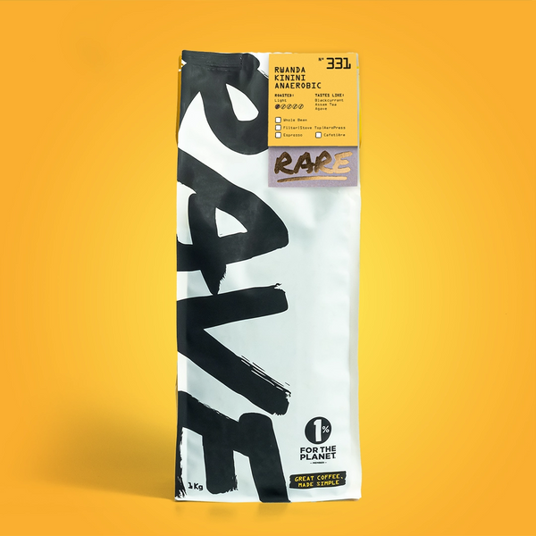 A white RAVE COFFEE bag with bold black letters and a yellow label reading "Rwanda Kinini Anaerobic Nº 331" from Kinini Washing Station sits on a solid yellow background, also featuring the 1% for the Planet logo.