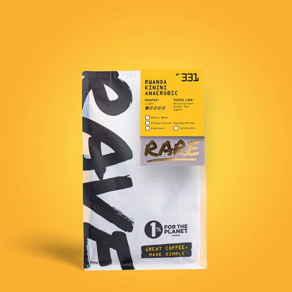 A white RAVE COFFEE bag with a yellow accent displays Rwanda Kinini Anaerobic Nº 331. Showcasing fruit-forward beans from Kinini Washing Station, it sits on a yellow background. 1% for the Planet. Great Coffee, Made Simple.