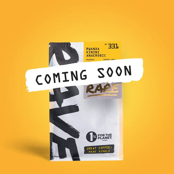 A coffee package labeled RARE and COMING SOON, set on a yellow background. It features RAVE COFFEE’s Rwanda Kinini Anaerobic Nº 331 from the Kinini Washing Station, known for its fruit-forward profile. Includes 1% For The Planet.