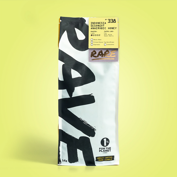 A white coffee bag with bold black "RAVE COFFEE" text stands upright on yellow. The top label features Indonesia Sesongot Anaerobic Honey Nº 338, honey processing, and 1% For The Planet among other details.