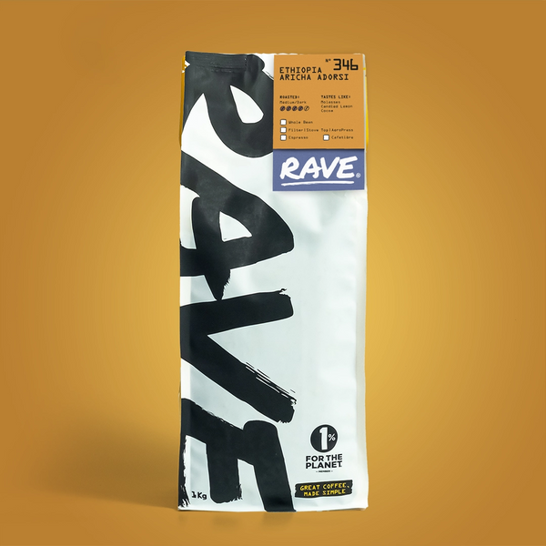 A bag of RAVE COFFEE labeled Ethiopia Aricha Adorsi Nº 346 stands upright on a warm, golden background. The high-altitude coffee is packaged in a white bag with bold black RAVE text and yellow and purple label accents at the top.