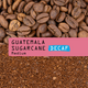 Close-up of whole coffee beans above ground coffee. Pink banner text: RAVE COFFEE Guatemala Sugarcane Decaf Nº 339, decaffeinated by the Sugarcane process. DECAF highlighted in blue.
