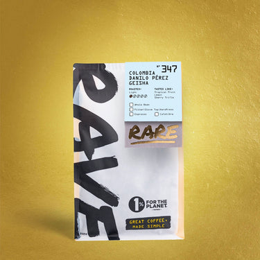 A bag of RAVE COFFEE Colombia Danilo Pérez Gesha Nº 347 features bold black text, a 1% for the Planet logo, and highlights tropical fruit notes on a gold textured background from this premium Huila Colombia gesha coffee.