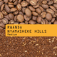 Coffee beans with a label indicating 'Rwanda Nyamasheke Hills Medium' on a brown background.