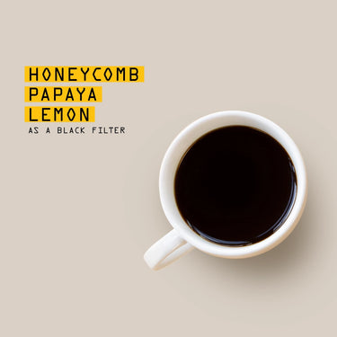 White mug with black coffee on a beige background, text overlay 'Honeycomb Papaya Lemon as a Black Filter'.