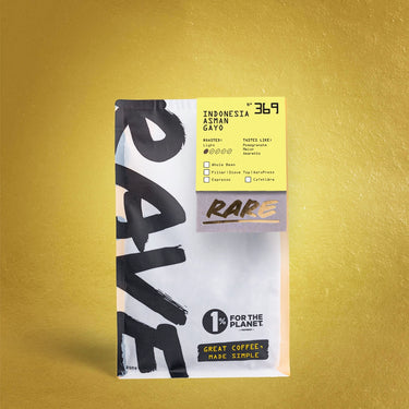 A bag of RARE coffee, specifically Indonesia Ashan Gayo, standing upright against a textured gold background. The packaging is white and black with a bright yellow label on the upper right containing product details.