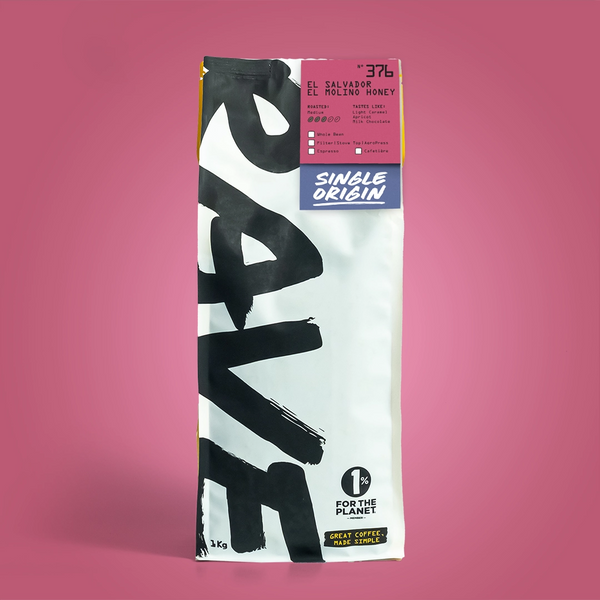 A single bag of coffee beans from the brand 'Rave' on a solid pink background. The bag is white with large black brushstroke lettering and features a pink and blue label at the top indicating 'Single Origin' and 'El Salvador'.