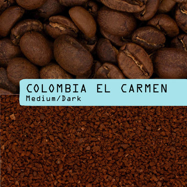 Close-up of whole coffee beans above ground coffee, divided by a blue label reading Colombia El Carmen Nº 50, highlighting this single origin coffee's quality and mycotoxin testing.