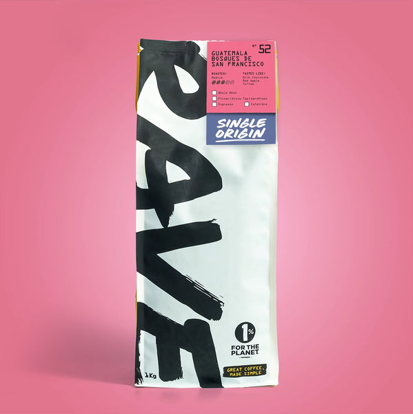 A bag of Guatemala Bosques de San Francisco Nº 52 coffee, with bold black text on white, a pink top label, and “1% for the planet” logo. This balanced sweet coffee offers red apple and toffee notes from Guatemalan beans.