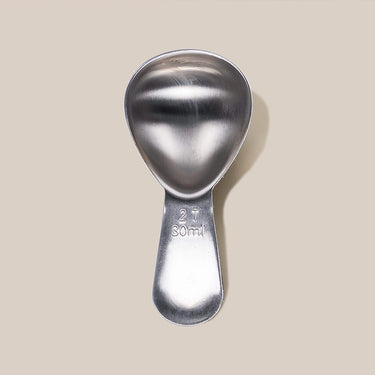 The Airscape Coffee Scoop by Planetary Design, a stainless steel spoon labeled 2 T and 30 ml on the handle, ideal for measuring coffee, is shown against a plain beige background.
