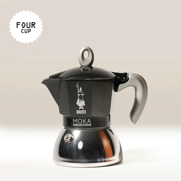 A black and silver Bialetti Moka Induction Stove Top Coffee Maker with a gray handle is pictured against a light background. "FOUR CUP" text highlights its capacity. Made in Italy by Bialetti for authentic espresso at home.