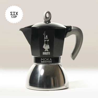 The Bialetti Moka Induction Stove Top Coffee Maker, in black and silver with a grey handle, is made in Italy, holds six cups, and is shown against a light background.