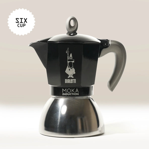 The Bialetti Moka Induction Stove Top Coffee Maker, in black and silver with a grey handle, is made in Italy, holds six cups, and is shown against a light background.