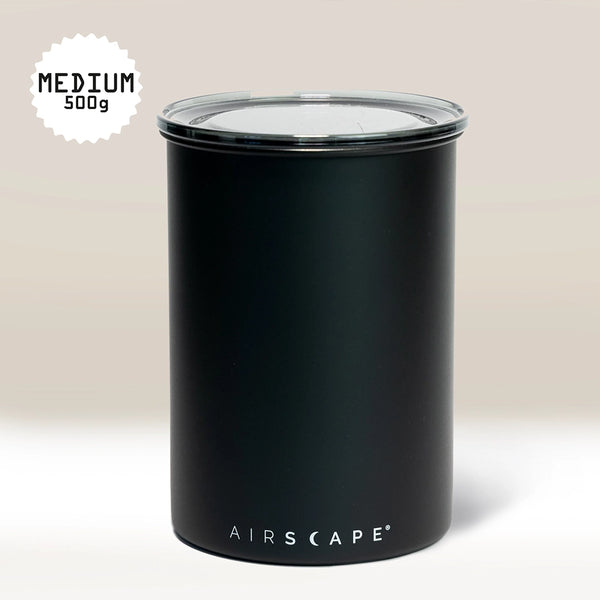 A Black Airscape Coffee Storage Container (500g, medium) by Planetary Design, with a clear lid for oxygen-free storage. Set against a light beige background; "MEDIUM 500g" is featured in a starburst at the top left corner.