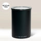 A Black Airscape Coffee Storage Container (500g, medium) by Planetary Design, with a clear lid for oxygen-free storage. Set against a light beige background; 