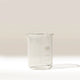The Labtek Borosilicate Glass Beaker, 100ml with measurement markings, stands transparent on a white surface against a light beige background—perfect as an espresso shot catcher for accurate pours.