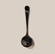 A shiny black stainless steel Rave Cupping Spoon from RAVE Coffee rests on a beige background, with “CAN I SIP IT?” engraved on the bowl—a playful nod to the art of coffee tasting and cupping.