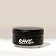 A small black RAVE Coffee container with a textured lid and “RAVE” written in white on the front, identified as the Rave 54mm Espresso Distributor and resembling an espresso distribution tool or coffee bed leveler, is placed against a plain, light background.