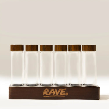 Six clear glass Coffee Bean Dosing Tubes (Set of 12) with dark wood lids standing in a matching wooden base.