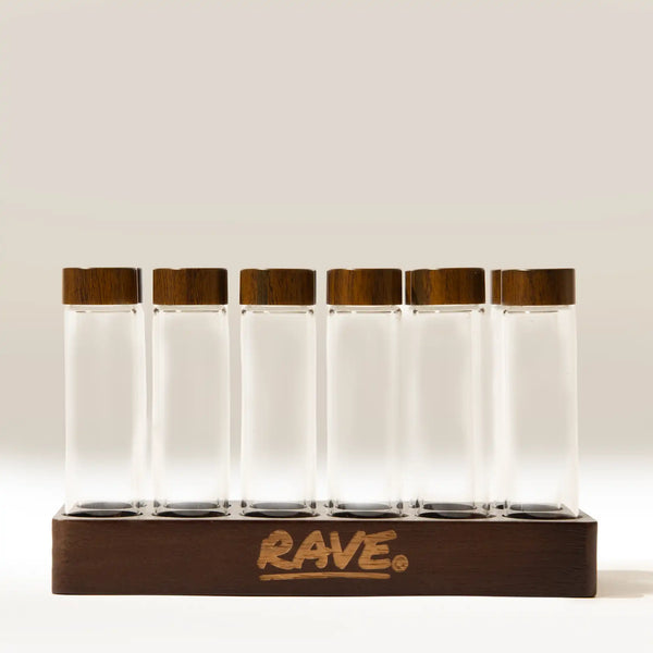 Six clear glass Coffee Bean Dosing Tubes (Set of 12) with dark wood lids standing in a matching wooden base.