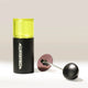 A black Comandante C40 coffee grinder with a neon yellow top stands upright beside its metal handle and a Comandante Polymer Bean Jar - Yellow, all resting on a light surface.