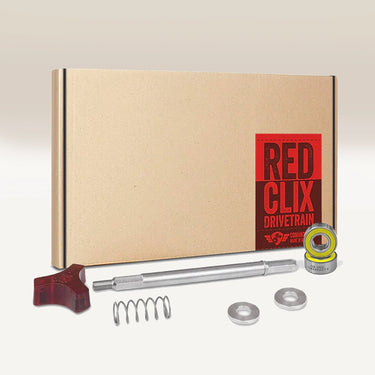 The Comandante RX35 Red Clix Drivetrain Set includes a brown box, red tool, metal rod, spring, washers, and a small bearing—ideal for specialty coffee espresso. The box features a red RX35 RED CLIX label. Brand: Comandante.