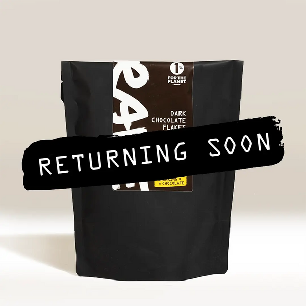 A black package of RAVE COFFEE Drinking Chocolate Flakes stands upright against a plain background, featuring a bold black banner with "RETURNING SOON" in white. Perfect for making rich and delicious drinking chocolate.