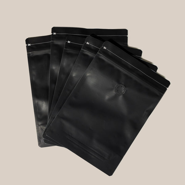 Five Ravecoffee Zip Lock Bags with Degassing Valve are fanned out on a light beige background. Each resealable bag features a small one-way valve near the top to help keep your coffee fresh. Set includes 5 bags.