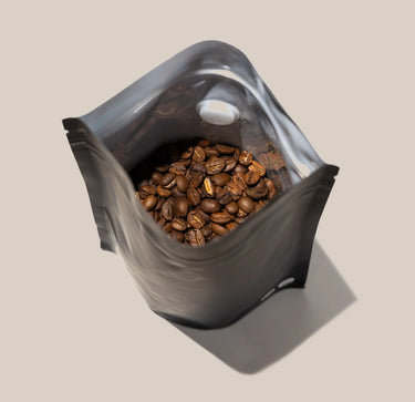 A set of Ravecoffee Zip Lock Bags with Degassing Valve x5, shown partially open and filled with roasted coffee beans, is seen from above against a plain beige background.