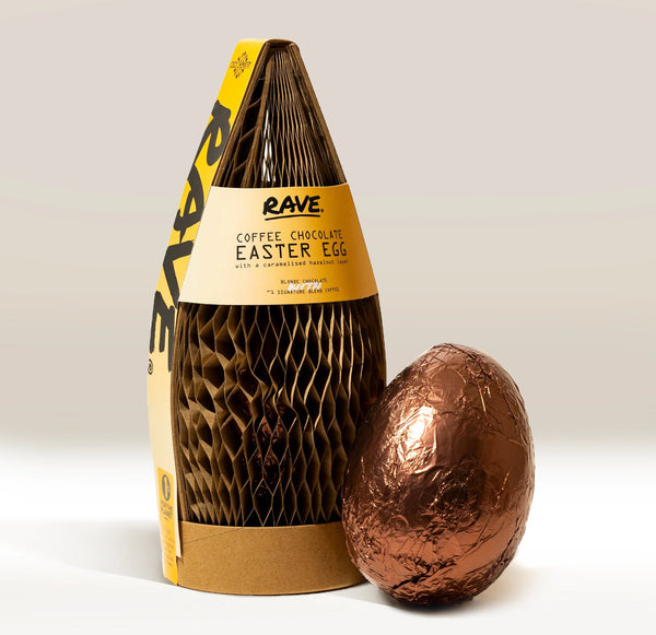 A foil-wrapped RAVE COFFEE Coffee Chocolate Easter Egg stands by its yellow and brown packaging, featuring honeycomb-textured paper wrapping with hints of blonde chocolate and caramelised hazelnuts.