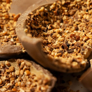 Close-up of RAVE COFFEE’s Coffee Chocolate Easter Egg, featuring a detailed texture of the smooth chocolate shell and caramel filling, topped with caramelised hazelnuts.