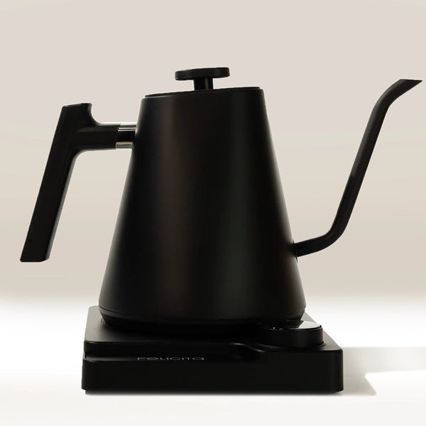The Felicita Square Pour Over Electric Kettle by Felicita, in matte black, features precision temperature control, a long gooseneck spout, and a modern handle design on its rectangular base, set against a plain light background.