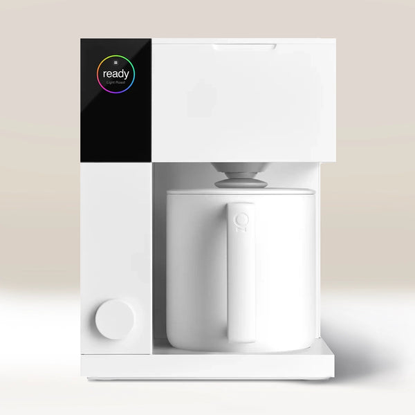 The Fellow Aiden Precision Drip Filter Coffee Maker by Fellow is a modern, minimalist white coffee maker with customizable temperature controls, a digital "ready" display, and a large white mug under the dispenser on a neutral background.