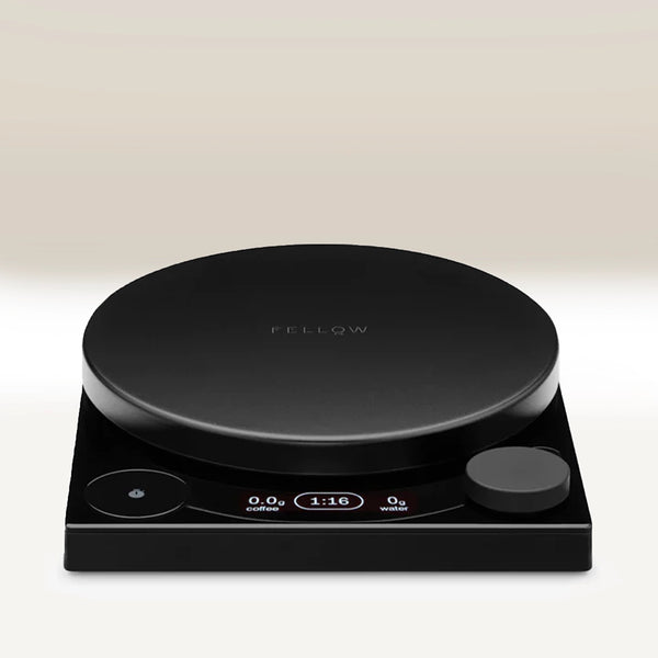 The Fellow Tally™ Pro Precision Scales by Fellow is a sleek black digital coffee scale with Brew Assist Mode, a round surface, display screen, and control knobs on a square base. It measures pour-over coffee weight, time, and water.